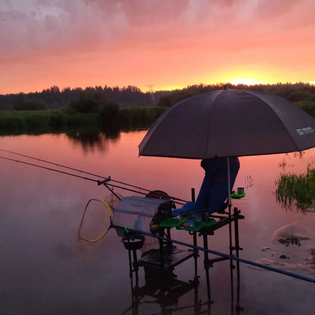 Оснащенное место для рыбалки с открытым зонтиком на закате для РА