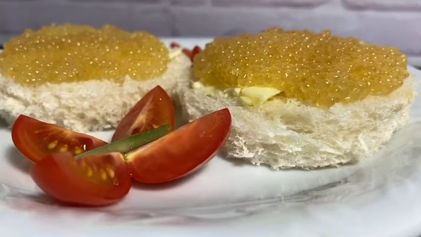 Бутерброды с маслом и икрой на тарелке с нарезанными помидорами 2