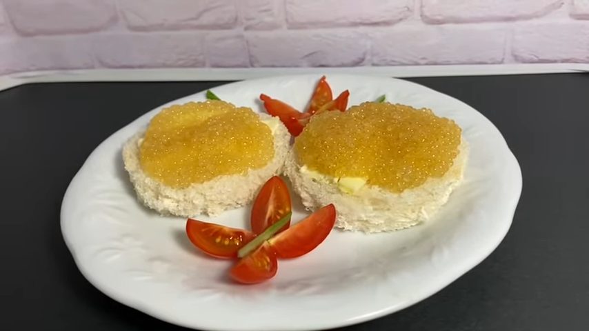 Бутерброды с маслом и икрой на тарелке с нарезанными помидорами