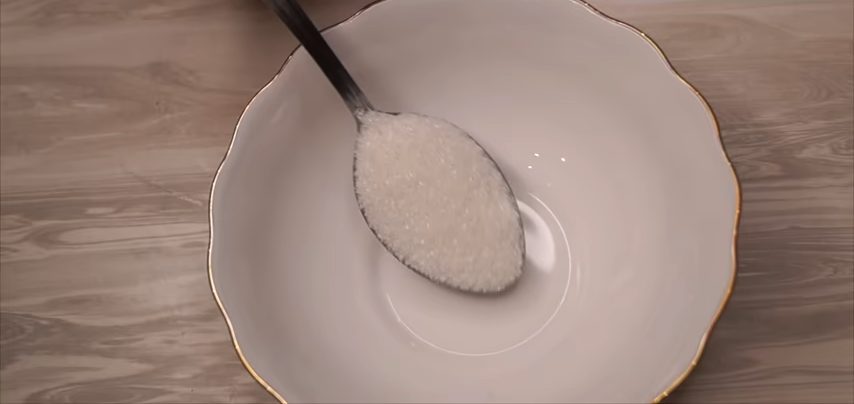Столовая ложка с сахаром в миске